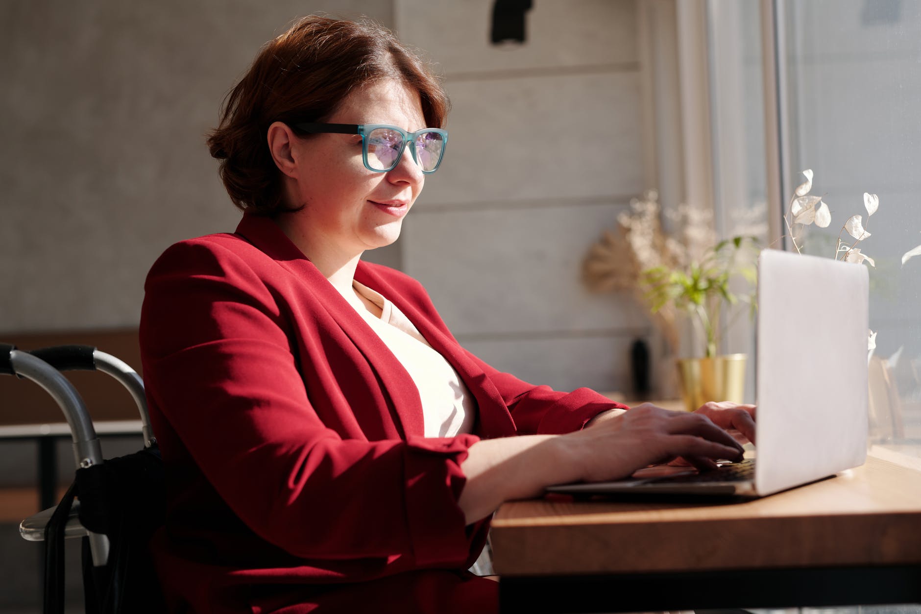 Woman wearing glasses and red jacket works at desk