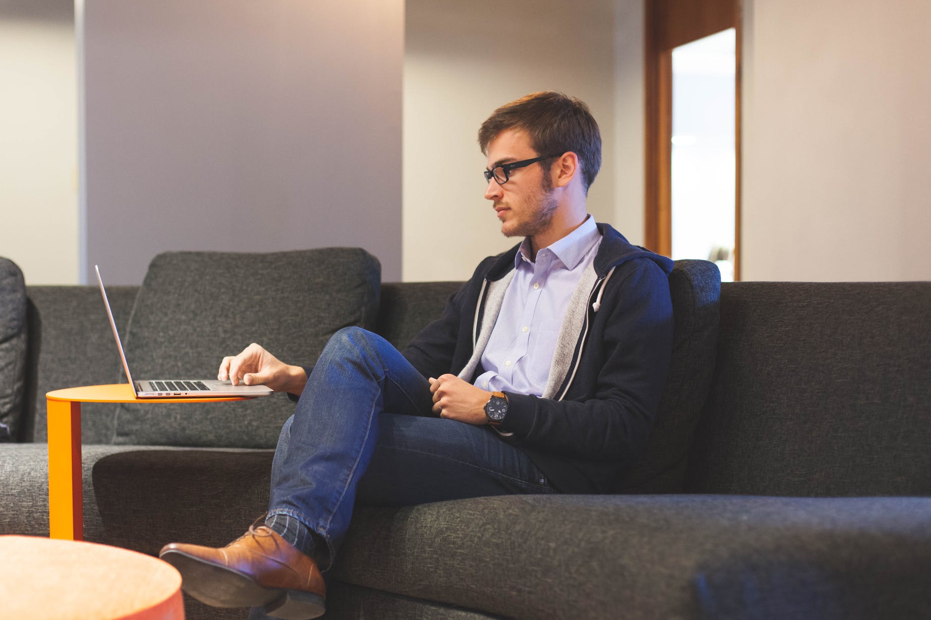 Man sitting on large couch using his laptop