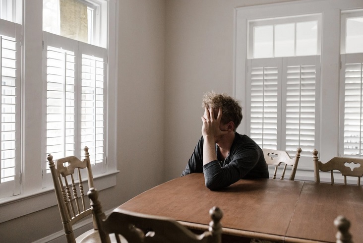 man leaning on table with head in hand